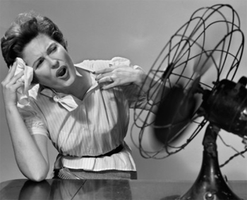 Menopause - Symptoms and How to Cope. Black-and-white photo of a woman fanning herself and wiping her forehead, showing discomfort from heat or a hot flush often associated with menopause.
