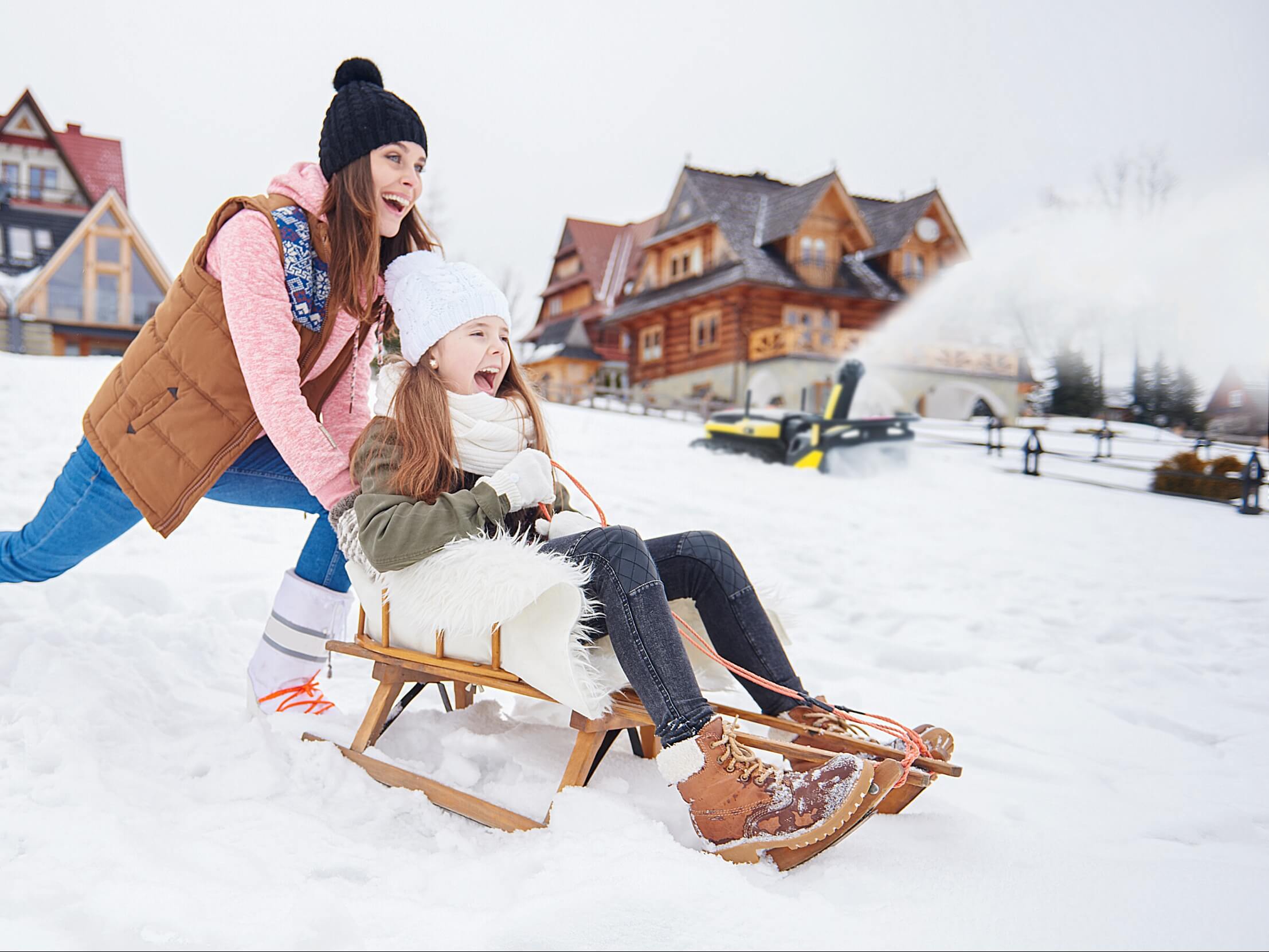 A battery powered snow blower is clearing snow while the user is having fun.