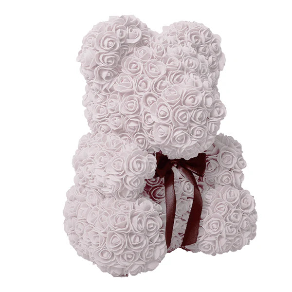 A teddy bear composed of white artificial roses with a dark brown ribbon bow tied at the front.