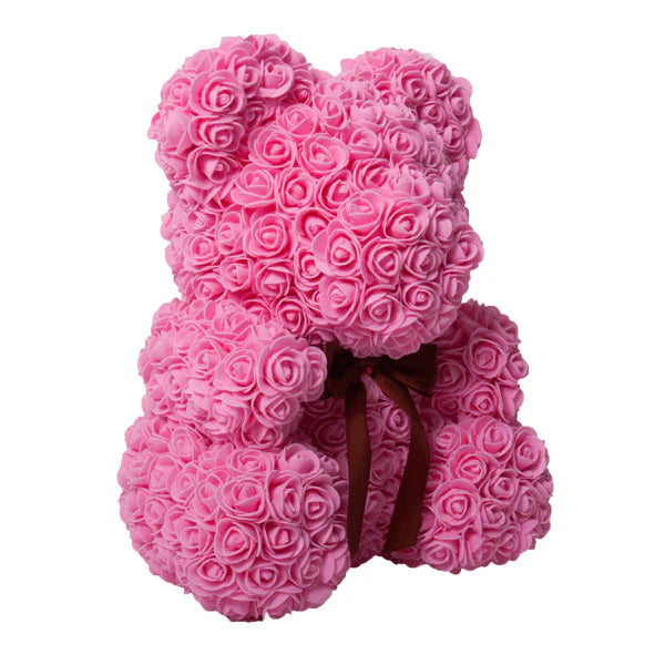 A teddy bear crafted from pink artificial roses, featuring a dark brown ribbon bow around its neck