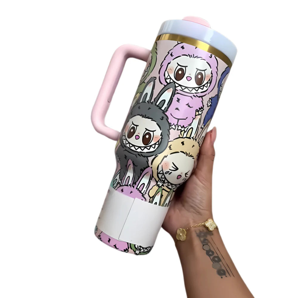 Hand holding a colorful 40 oz tumbler featuring multiple Labubu character illustrations, with a pink handle and gold accent near the lid.