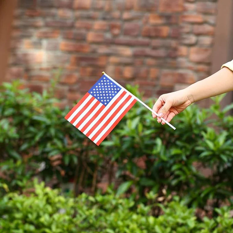 Miniature USA and UK flags laid out next to a stack of assorted folded international flags.