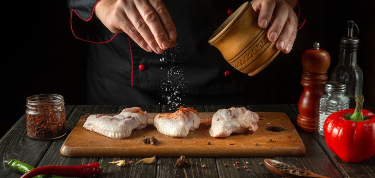 a chef is seasoning food with clean ingredients